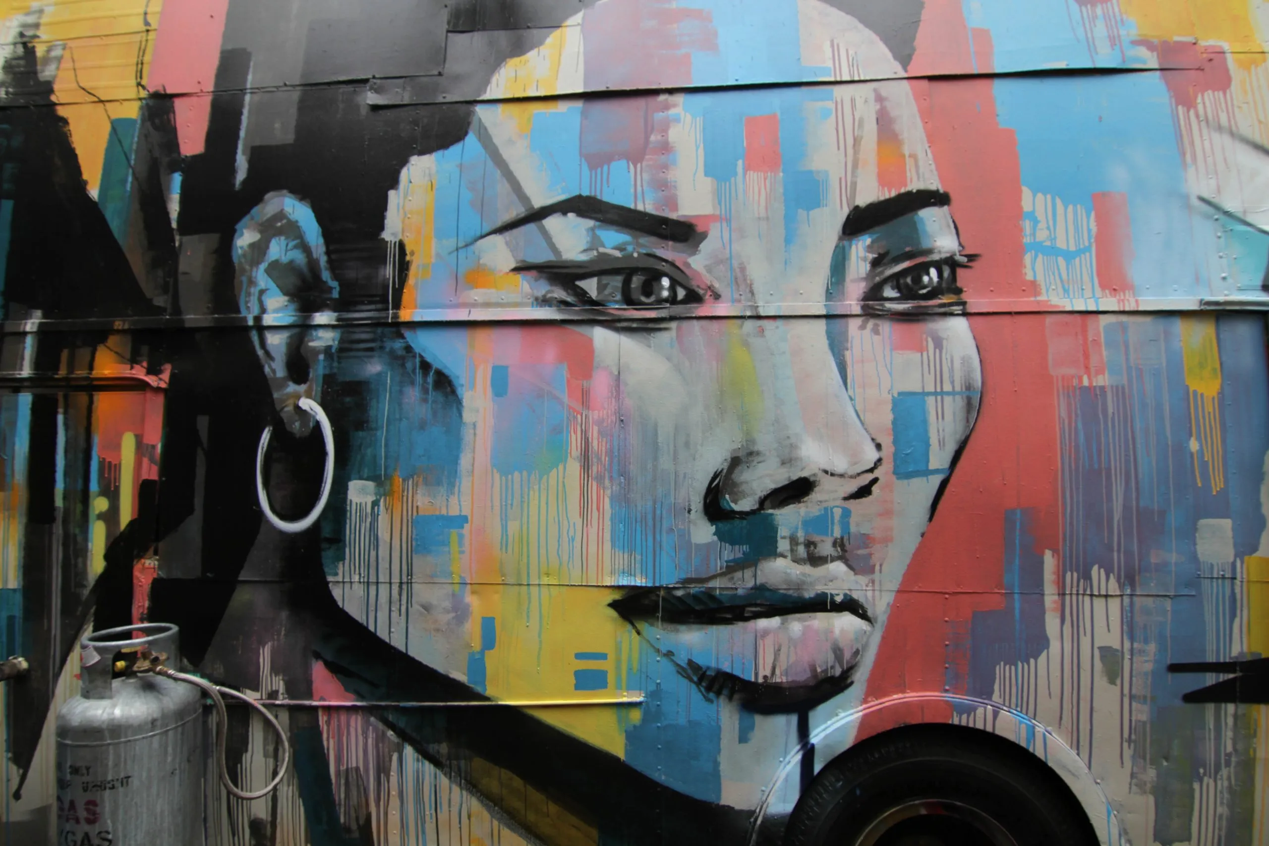 Large-scale mural of a woman's face in bold colour blocks, painted on the side of a truck trailer