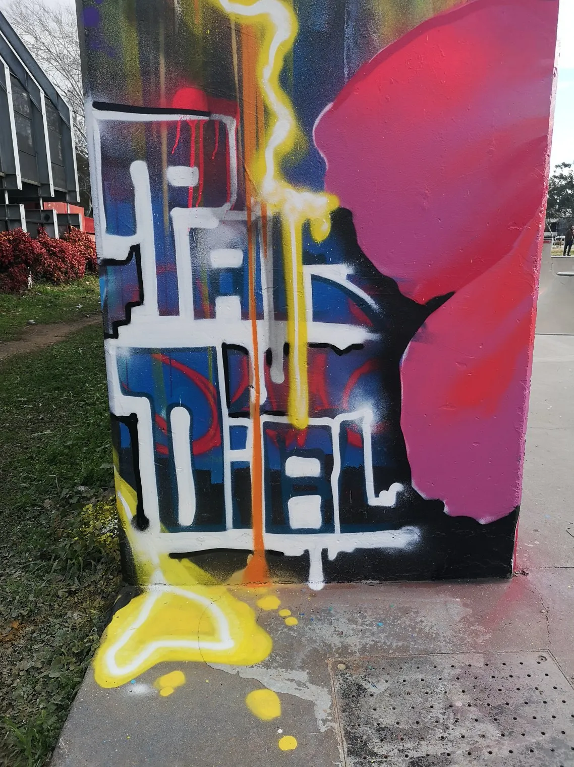 Wildstyle graffiti lettering in white and blue with red and yellow accents on a concrete block