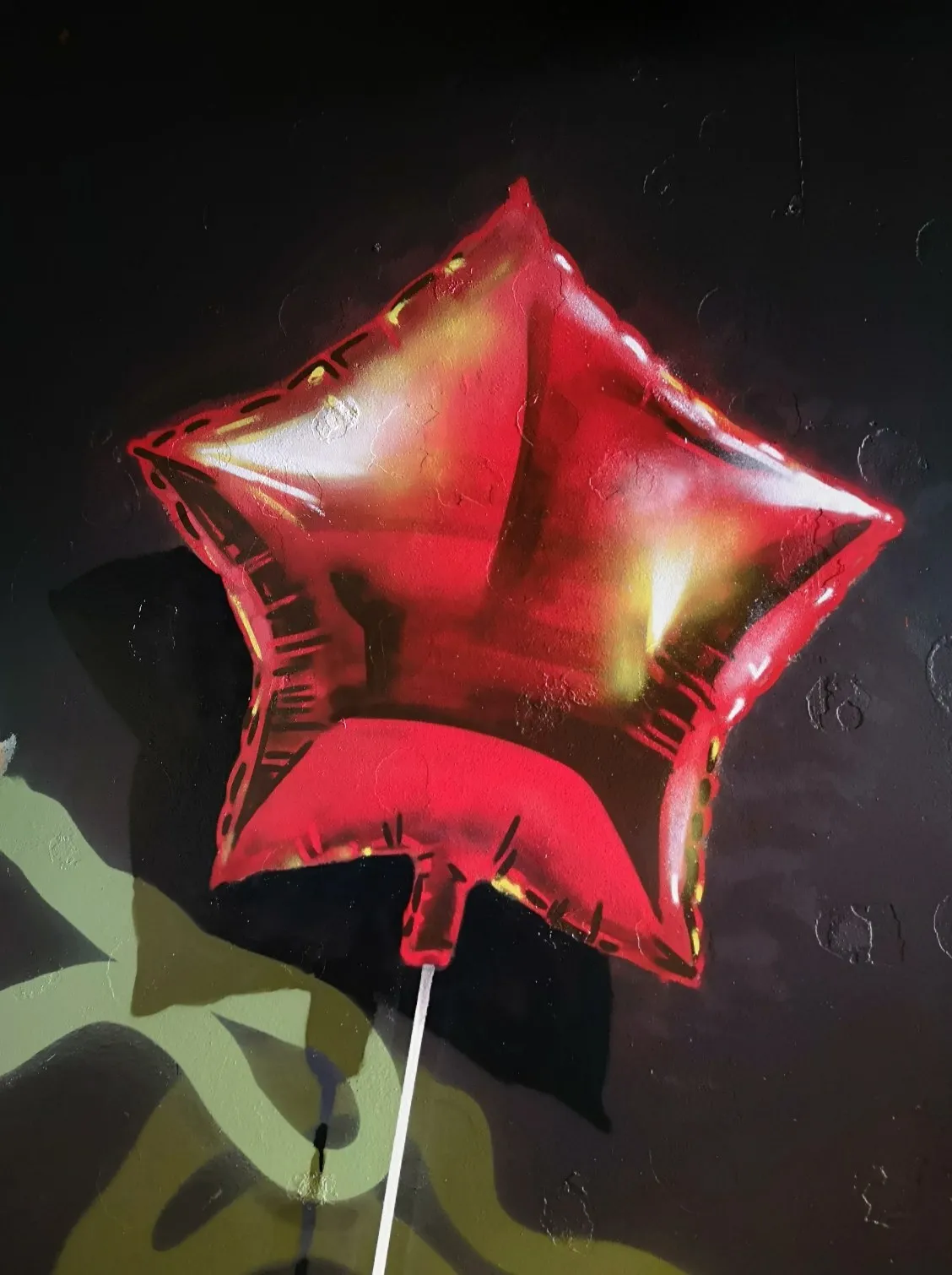 Mural of a shiny red star-shaped balloon on a dark background